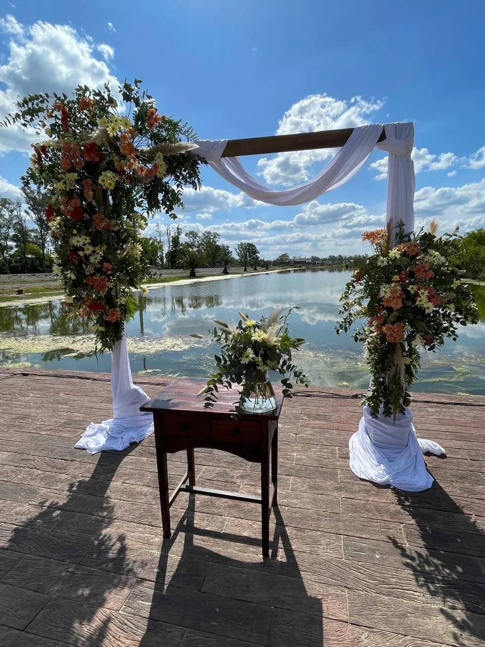 Arco de flores y tela blanca frente a una laguna en Maschwitz